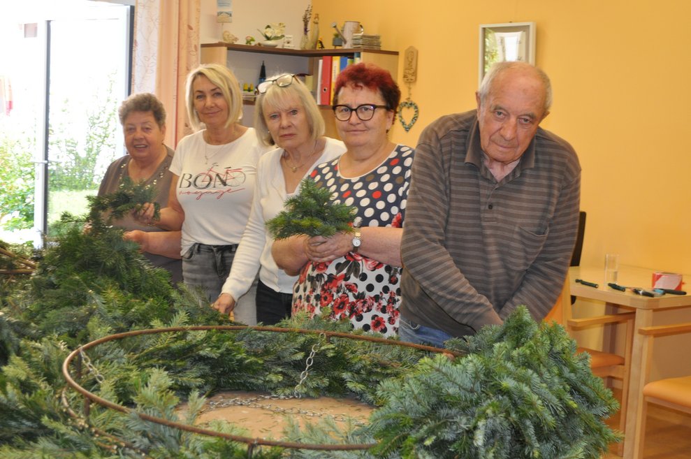 Einige Personen beim Flechten eines Kranzes für den Maibaum
