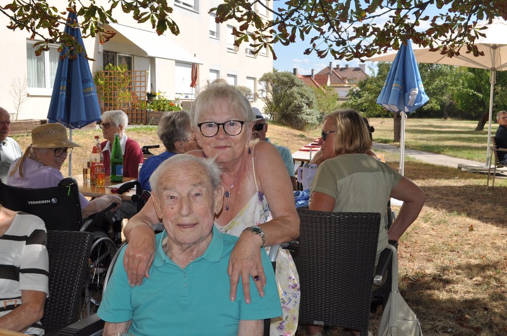 ein Mann im Rollstuhl und eine Frau im Garten beim Gartenfest