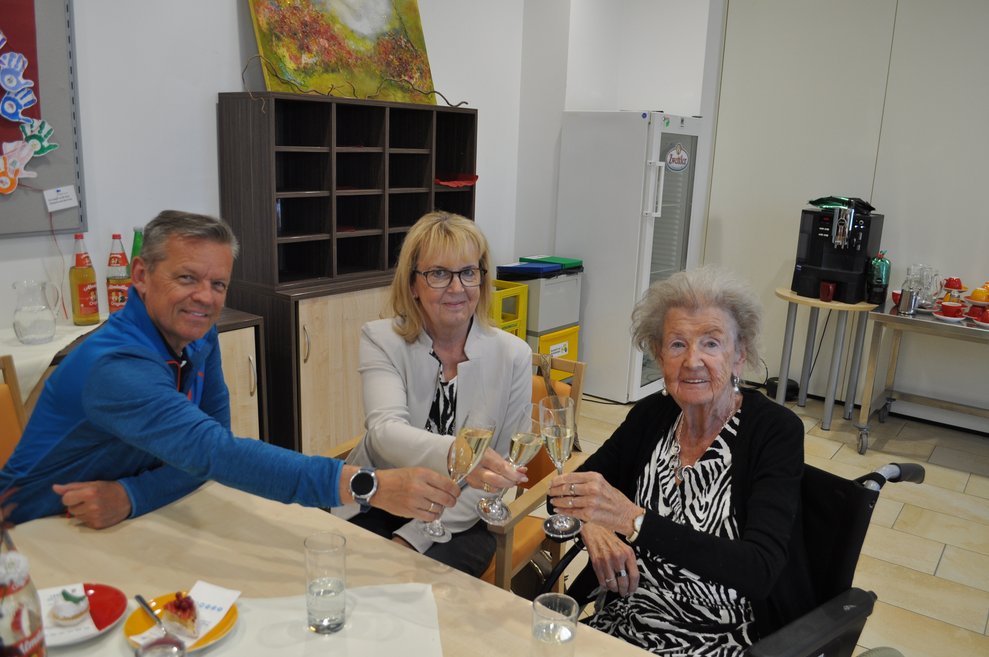 ein Mann und zwei Frauen stoßen mit Sekt an