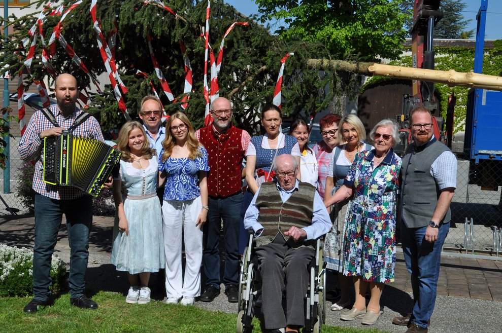 eine Gruppe von Menschen vor dem Maibaum