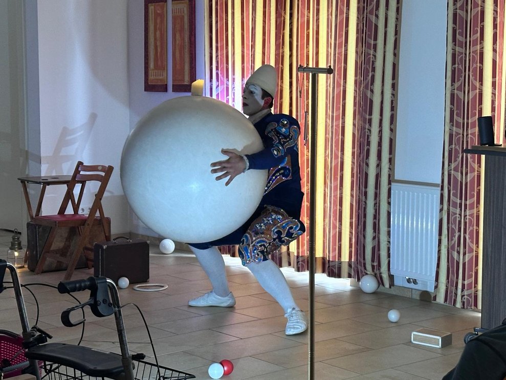 ein Clown bei seiner Vorstellung der einen großen weißen Ball festhält