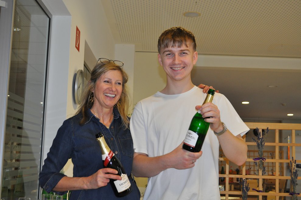 eine Frau und ein junger Mann mit Sektflaschen in der Hand