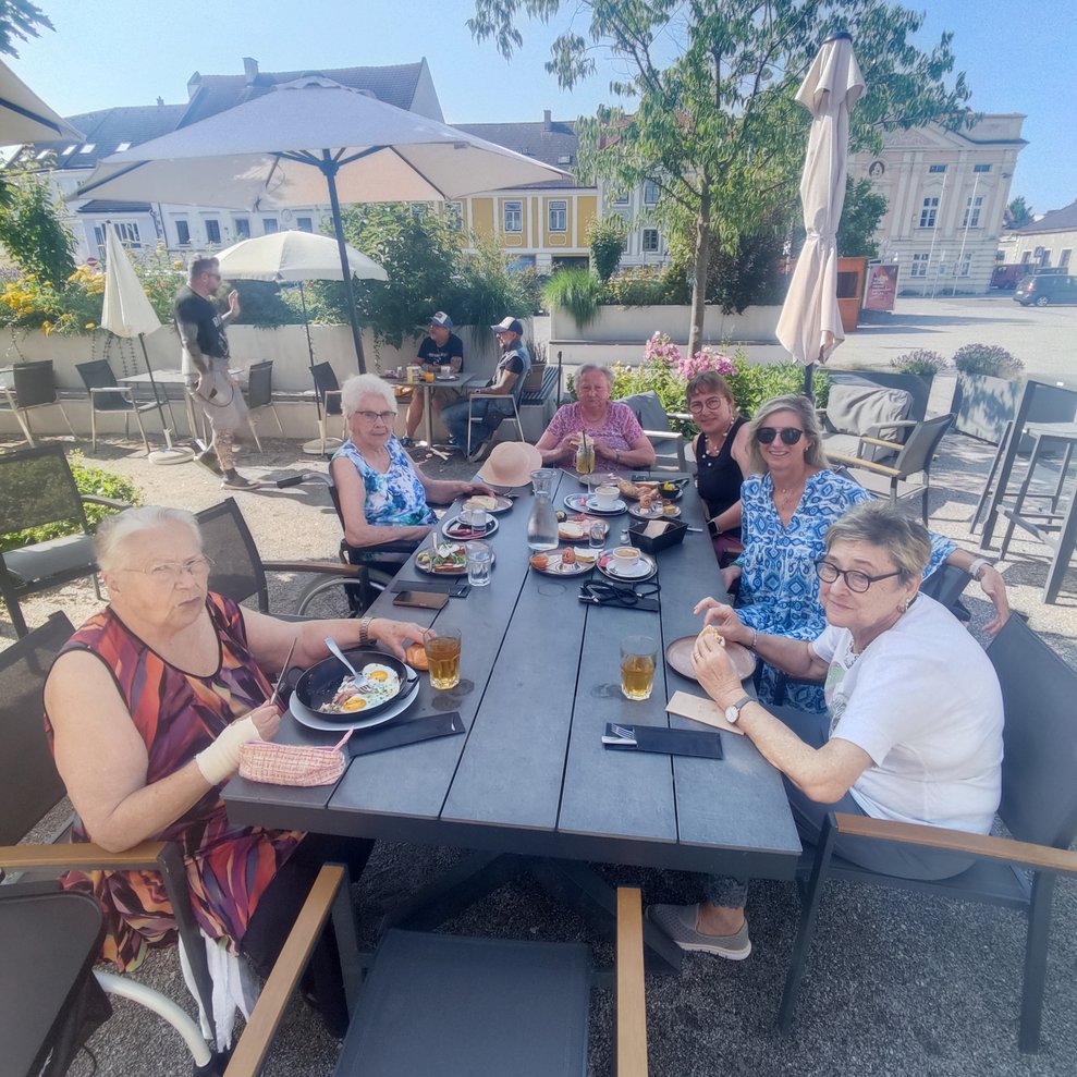 eine Gruppe von älteren Menschen und Betreuerinnen beim Frühstück im Kaffeehaus