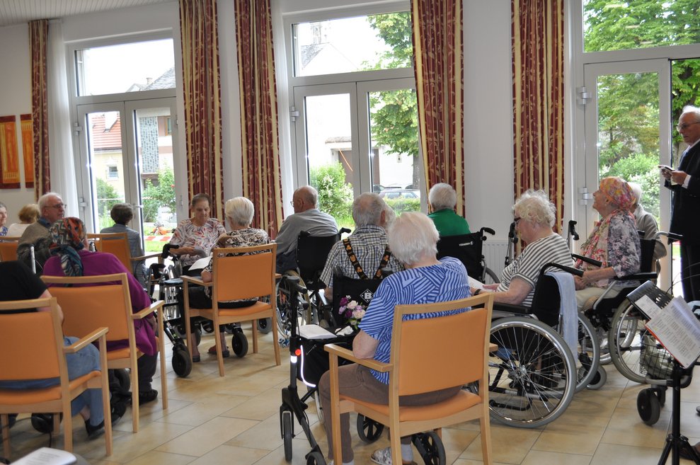 mehrere ältere Menschen im Seminarraum und sehen nach draußen in den Garten