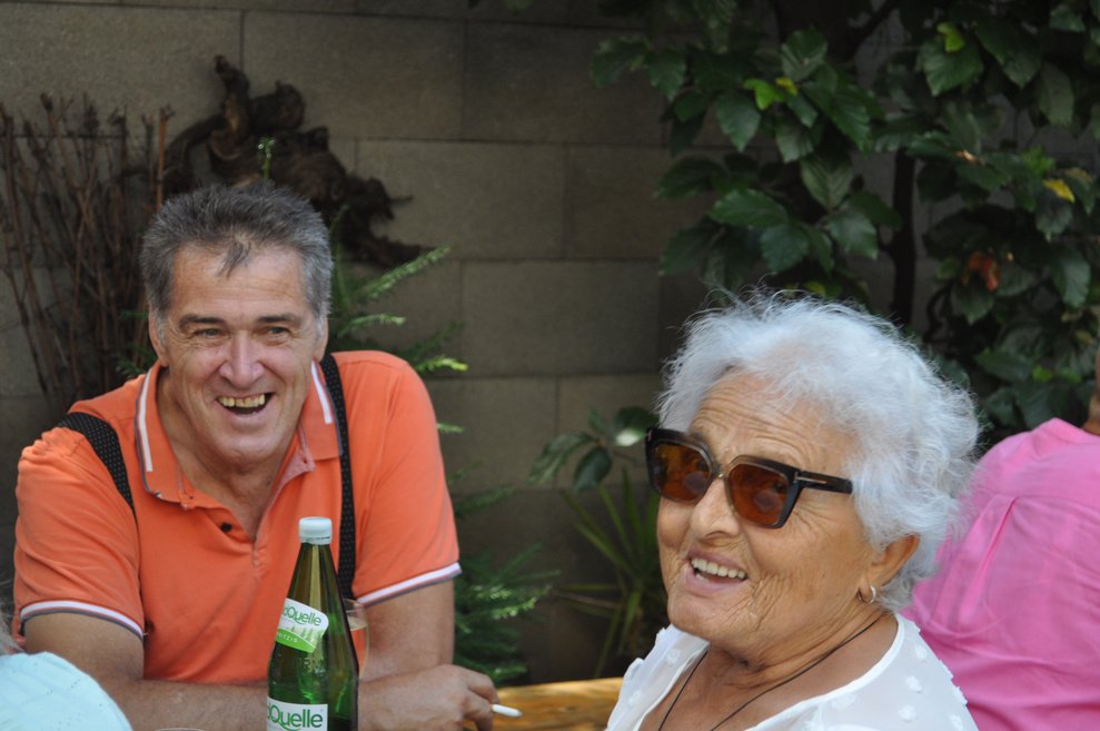 Zwei Personen sitzen bei Tisch auf einer Heurigengarnitur