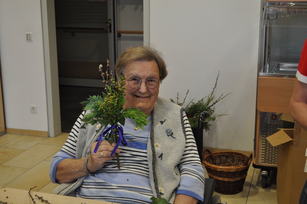 eine ältere Dame mit einem fertig gebundenen Palmbuschen 