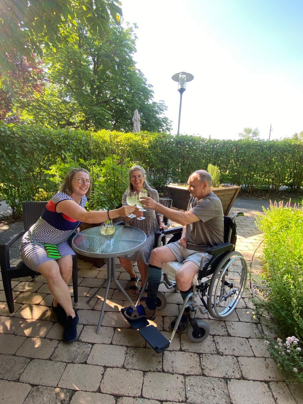 Drei Personen sitzen im Garten und trinken Melissensaft