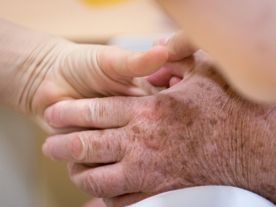 Eine Betreuerin hält die Hand einer Bewohnerin.