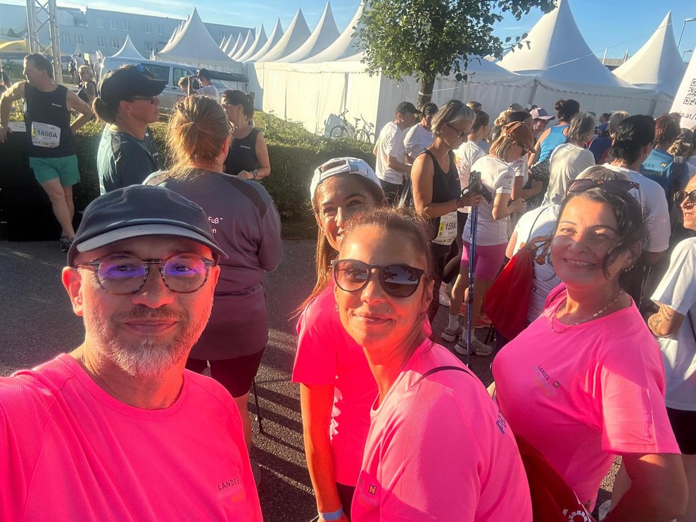 ein Mann und 3 Damen mit pinken T-Shirts, im Hintergrund Zelte