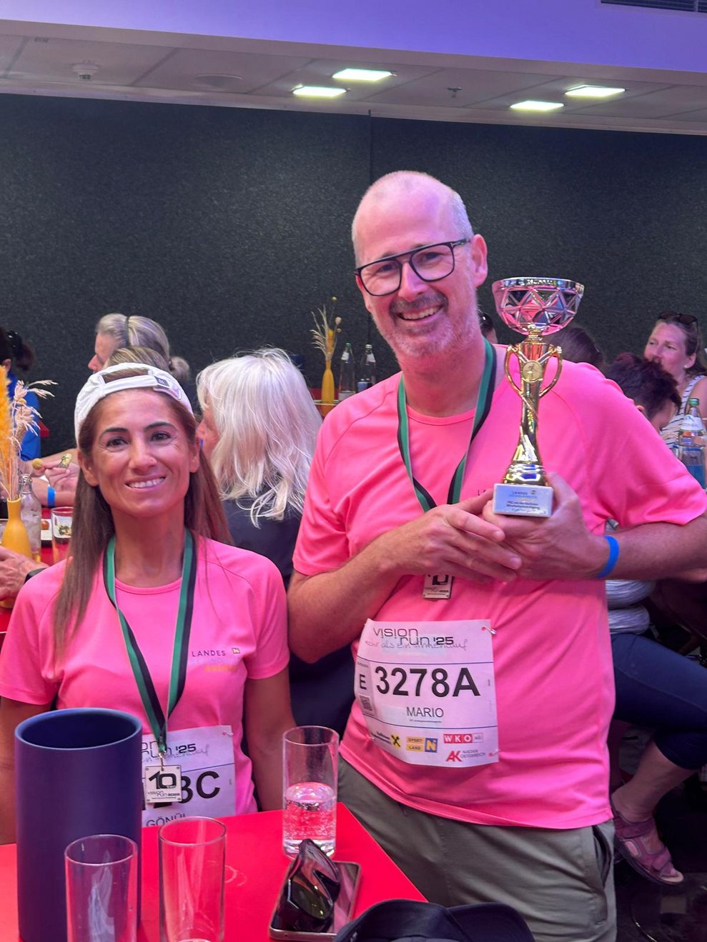 ein Mann und eine Frau mit pinken Sport T-Shirts, Medaillen und Pokal