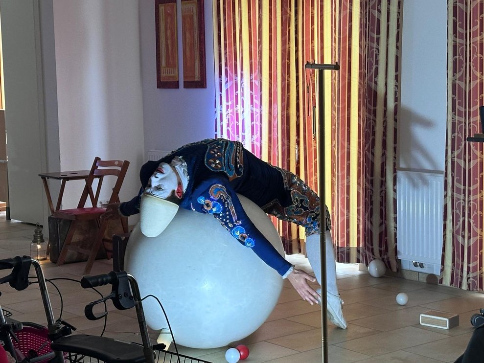 ein Clown bei seiner Vorstellung liegt mit dem Rücken auf einem großen weißen Ball