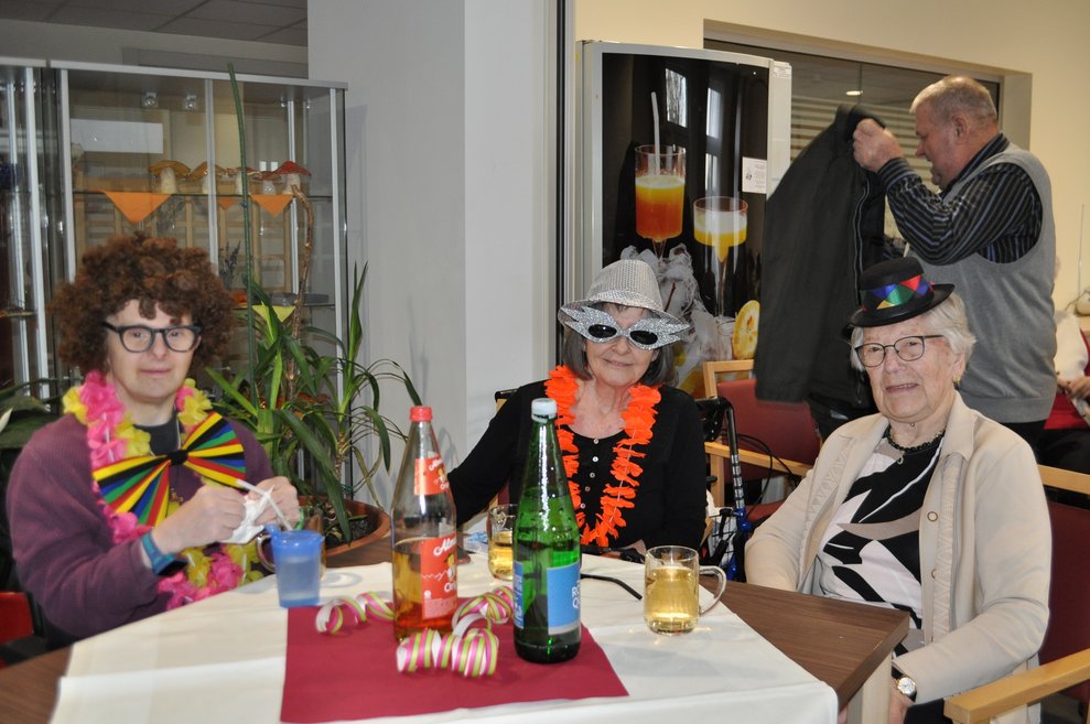 Drei Personen mit Hüten und Masken bei der Faschingsfeier